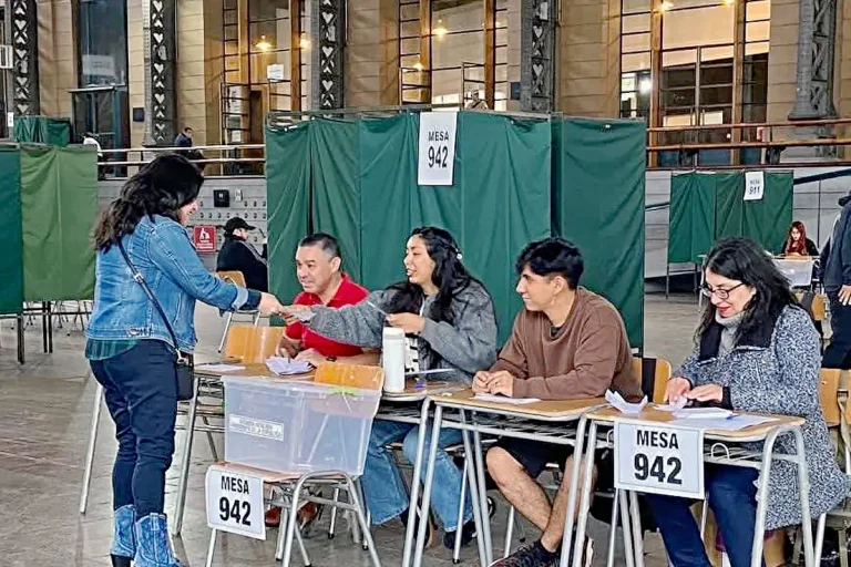 Mesa electoral con personas votando en Chile