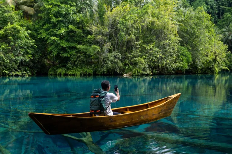 Hombre navegando en el rio con un celular en la mano.