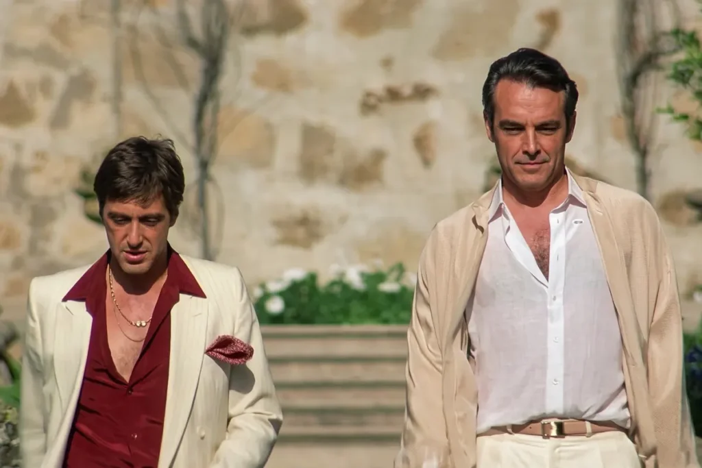 El mural de Marset recuerda una vieja anécdota: el supuesto encuentro de Suárez y Escobar viendo Scarface Lo esencial: Un mural hallado en un galpón del Urubó, Santa Cruz, durante los allanamientos vinculados al narcotraficante uruguayo Sebastián Marset, muestra a Marset, Pablo Escobar, Roberto Suárez Gómez, Chapo Guzman y el personaje ficticio Tony Montana reunidos alrededor de una mesa de billar. Por qué importa: El hallazgo revive un episodio real y poco conocido: Escobar y Suárez Gómez habrían visto juntos Scarface en los años ochenta, décadas antes de que su estética se convirtiera en símbolo recurrente del narcotráfico latinoamericano. Que un operativo contra Marset en 2025 descubra ese mismo imaginario en sus propiedades sugiere que la llamada "narcoestética" sigue funcionando como código de identidad y aspiración dentro del crimen organizado contemporáneo. El antecedente clave: Tres de las cuatro figuras del mural comparten un episodio documentado: Según el libro autobiográfico de Ayda Levy, en 1983, Pablo Escobar y Roberto Suárez Gómez habrían visto juntos una copia privada de Scarface antes de que la película se estrenará en Sudamérica. Suárez Gómez era entonces el mayor productor de cocaína de Bolivia, conocido como "El Rey de la Cocaína", mientras Escobar consolidaba el Cartel de Medellín. El boliviano habría identificado que el personaje de Alejandro Sosa —el empresario boliviano con contactos políticos y militares que provee cocaína a Montana— estaba modelado, al menos en parte, sobre su propia figura. Al final de la velada, ambos capos habrían bromeado con la posibilidad de demandar a Universal Pictures y cobrar regalías por los derechos del film. Qué dicen: Ayda Levy, viuda de Suárez Gómez, menciona en su libro que en algún momento de la proyección el boliviano detuvo el film, señaló a Escobar y dijo: "¿Quién les dijo que Montana era cubano y vivía en Miami? Si acá todos sabemos que mi Tony Montana es paisa y está sentado a mi lado." y que Escobar habría estallado en carcajadas. Entre líneas: Scarface fue concebida como una advertencia: Oliver Stone escribió a Tony Montana como un retrato de la autodestrucción, y la crítica la recibió con hostilidad en 1983. Fueron los propios narcos latinoamericanos quienes la rescataron del olvido a través del VHS, convirtiéndola en su película de cabecera antes de que Hollywood comprendiera lo que había creado. Qué sigue: El comandante de la Policía, general Mirko Sokol, confirmó que los allanamientos continuarán en los próximos días para desarticular por completo la organización de Marset. La DEA conducirá el proceso judicial en Estados Unidos.