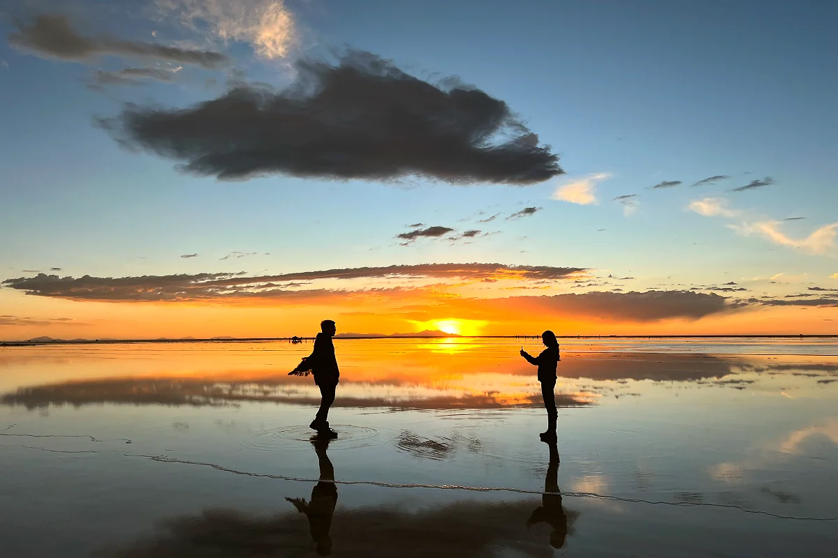 Salar de Uyuni al atardecer, con turistas sacando fotos.